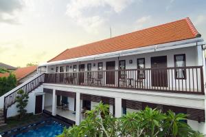 a building with a balcony and a swimming pool at Sanur Guest House in Sanur