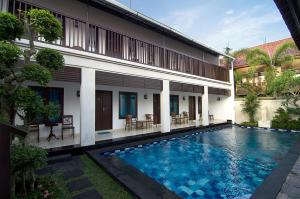 a villa with a swimming pool in front of a building at Sanur Guest House in Sanur