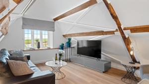 een woonkamer met een bank en een flatscreen-tv bij The Studio Cottage in Chipping Campden