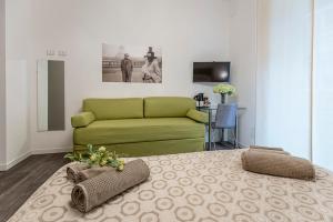 uma sala de estar com uma cama verde e um sofá em B&B Corso Diaz em Ravenna