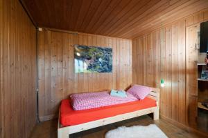 a small room with a bed in a wooden wall at Cottage Obereichholzberg in Weesen