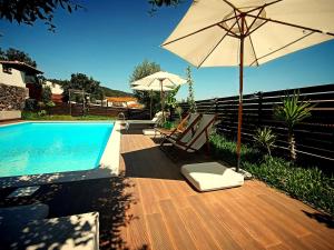 um guarda-sol e cadeiras junto a uma piscina em Quinta do Chafariz em Algaça