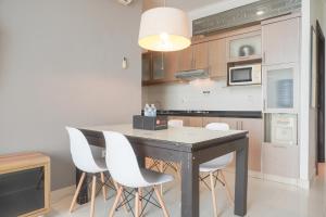 a kitchen with a black table and white chairs at Homey and Comfort Stay 2BR Bellezza Apartment By Travelio in Jakarta