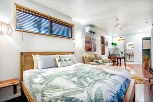 a bedroom with a large bed and a living room at Airlie Beach Eco Cabins - Adults Only in Airlie Beach