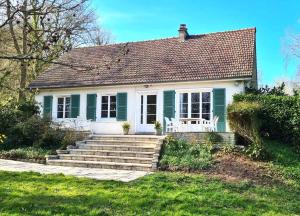 a small green and white house with a porch at LA TANIÈRE in Gueures