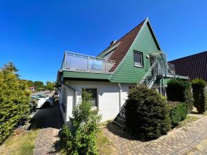 a green and white house with a balcony at Lange Straße by Restaurant WIESENAU in Prerow