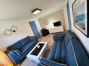 a living room with blue couches and a tv at Lange Straße by Restaurant WIESENAU in Prerow