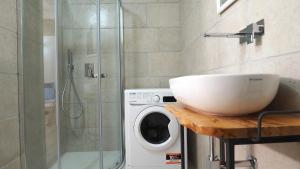 a bathroom with a washing machine and a glass shower at Corte Nizza in Taviano +23 photos