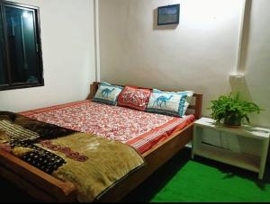 a bedroom with a bed and a table with a plant at Greenbliss Homestay By StayApart in Gorubathān