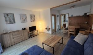 un salon avec un canapé bleu et une table dans l'établissement Ferienhaus Nr 91, Kategorie Komfort, Feriendorf Hochbergle, Allgäu, à Karlsebene