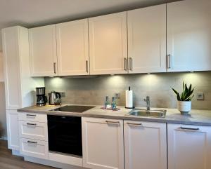 a kitchen with white cabinets and a sink at NEU 2025 - Fewo mit Meerblick & Flair in Harrislee