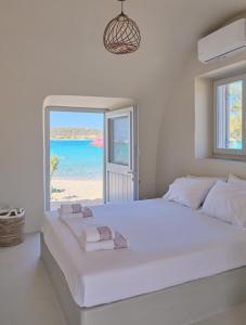 a white bedroom with a large bed with a view of the beach at Villa Aqua Blue 1 - Etheras properties in Diakofti