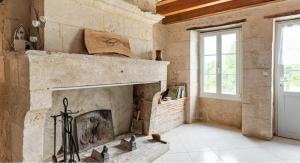 a stone fireplace in a living room with a window at Eugénie in Saint-Quentin-de-Chalais