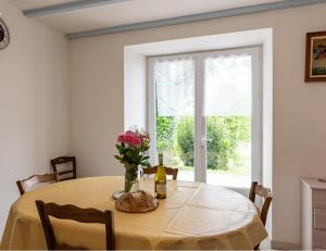 a table with a vase of flowers and a bottle of wine at Eugénie in Saint-Quentin-de-Chalais