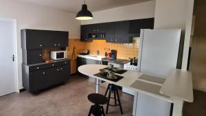 a kitchen with black cabinets and a white refrigerator at Appartement dans maison au calme in Oyonnax
