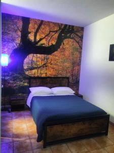 a bedroom with a bed with a tree mural on the wall at SIM residence in Maniago