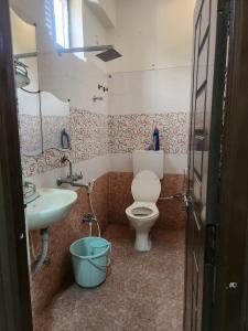 a bathroom with a toilet and a sink and a bucket at skhanda family stay in Maula Ali