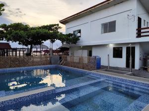a swimming pool in front of a house at Calishores Beachfront Resort in Morong