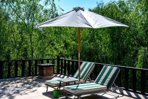 two chairs and an umbrella on a deck at Wineport Lodge Agva Riverside Hotel & Winery in Ağva
