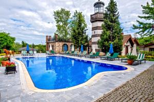a swimming pool with a lighthouse in the background at Wineport Lodge Agva Riverside Hotel & Winery in Ağva