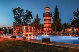 a lighthouse in front of a building with a pool at Wineport Lodge Agva Riverside Hotel & Winery in Ağva