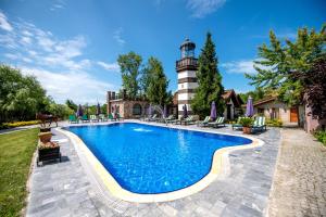 a swimming pool with a lighthouse in the background at Wineport Lodge Agva Riverside Hotel & Winery in Ağva