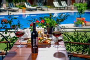 a table with two glasses of wine and a plate of food at Wineport Lodge Agva Riverside Hotel & Winery in Ağva