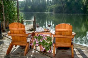 two chairs and a table with flowers on a dock at Wineport Lodge Agva Riverside Hotel & Winery in Ağva