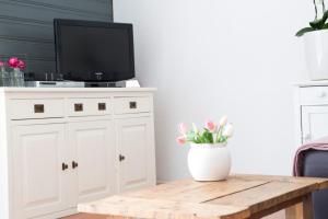 ein Wohnzimmer mit einem TV und einem Tisch mit Blumen in der Unterkunft Apartment Boven Jan 572 in Den Helder