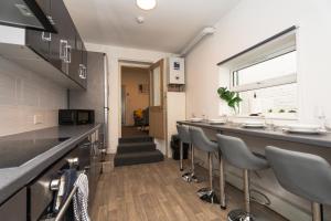 a kitchen with a long bar with stools at Thameside Terrace - 4Bed 3Bath near Purfleet train station in Purfleet