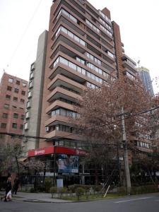 um edifício alto com um sinal em frente em Encomenderos Suites - Apartamentos Amoblados em Santiago