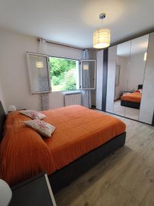 a bedroom with a large orange bed and a mirror at Casa Milona in Castelveccana
