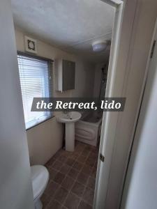 Un baño con inodoro, lavabo y ventana. en The Retreat Lido Beach - Lido Beach Prestatyn, en Prestatyn