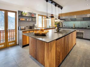 a large kitchen with wooden cabinets and a large island at Chalet 5★, 15 pers, pied des pistes, spa extérieur, 7 chambres - FR-1-304-308 in La Clusaz
