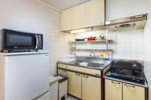 eine kleine Küche mit Spüle und Mikrowelle in der Unterkunft 桜音屋 in Susakiuramachi