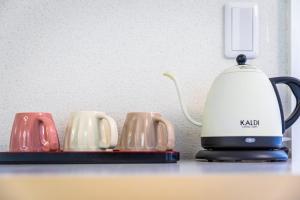 einen Wasserkocher und vier Kaffeetassen auf der Theke in der Unterkunft 桜音屋 in Susakiuramachi