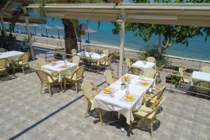 a restaurant with tables and chairs and the ocean at Sunset Hotel in Xiropigado