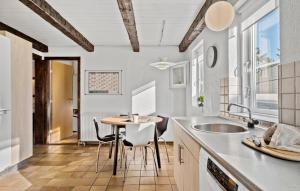 a kitchen with a table and chairs and a sink at 5 Bedroom Nice Home In Blokhus in Blokhus +18 photos