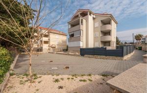 a apartment building and a tree in a parking lot at Awesome Apartment In Novalja With Wifi in Novalja