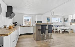 eine Küche mit weißen Schränken und Barhockern in der Unterkunft Beautiful Home In Haderslev With Sauna in Haderslev