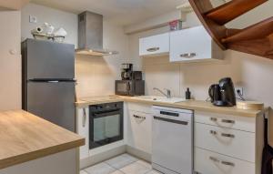 a small kitchen with white cabinets and a refrigerator at Lovely Home In Hauteville-Sur-Mer in Hauteville-sur-Mer