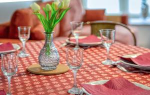 a table with wine glasses and a vase with flowers at Lovely Home In Hauteville-Sur-Mer in Hauteville-sur-Mer