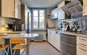 ヴェルノンにある3 Bedroom Awesome Home In Vernonの白いキャビネットとテーブル付きのキッチンが備わります。