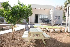 una mesa de picnic y sillas frente a una casa en Aviv BaGalille, en She'ar Yashuv