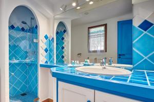 a blue bathroom with a sink and a shower at Résidence Belvedere de Palombaggia in Porto-Vecchio