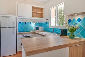 a kitchen with blue tiled walls and a white refrigerator at Résidence Belvedere de Palombaggia in Porto-Vecchio