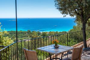 a table and chairs on a balcony with the ocean at Résidence Belvedere de Palombaggia in Porto-Vecchio