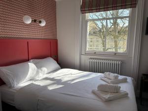 une chambre avec un lit blanc avec des serviettes dessus dans l'établissement St. David's Hotels Paddington, à Londres
