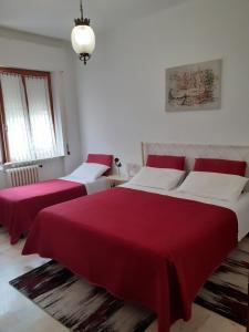 2 posti letto in una camera bianca con lenzuola rosse di Casa Dilva a Porto SantʼElpidio