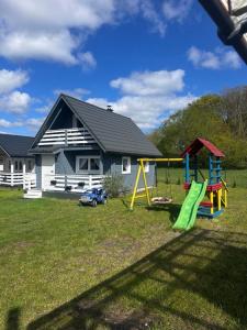 a house with a yard with a playground at Chatki przy Marinie in Wapnica